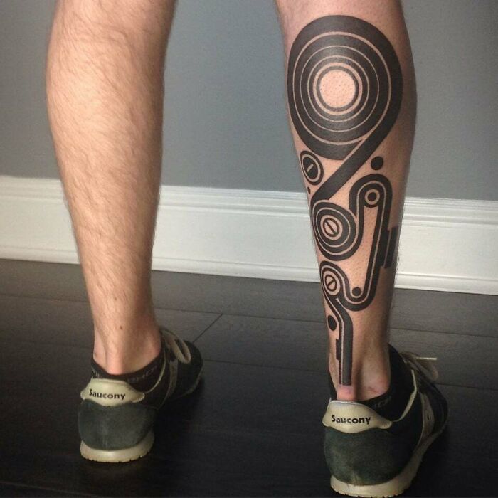 Abstract tattoo featuring bold geometric patterns on a calf, showcasing artistic self-expression and design.