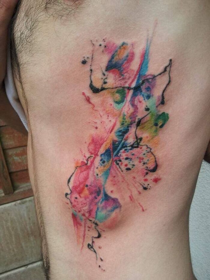 Colorful abstract tattoo showcasing artistry and self-expression on a person's side.