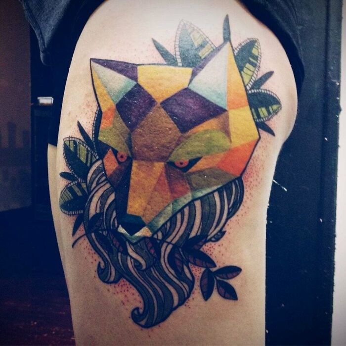 Abstract tattoo featuring a colorful geometric fox design with leaves and flowing shapes on an arm.