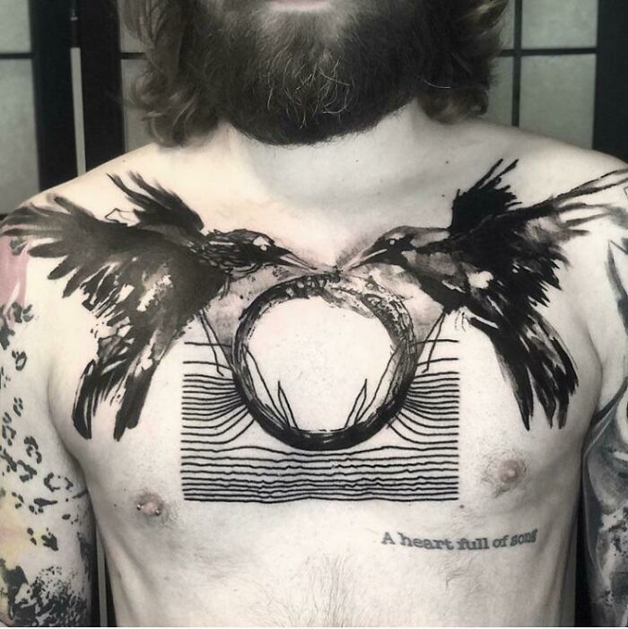 Abstract tattoo featuring birds and geometric shapes on a person's chest, showcasing artistry and self-expression.