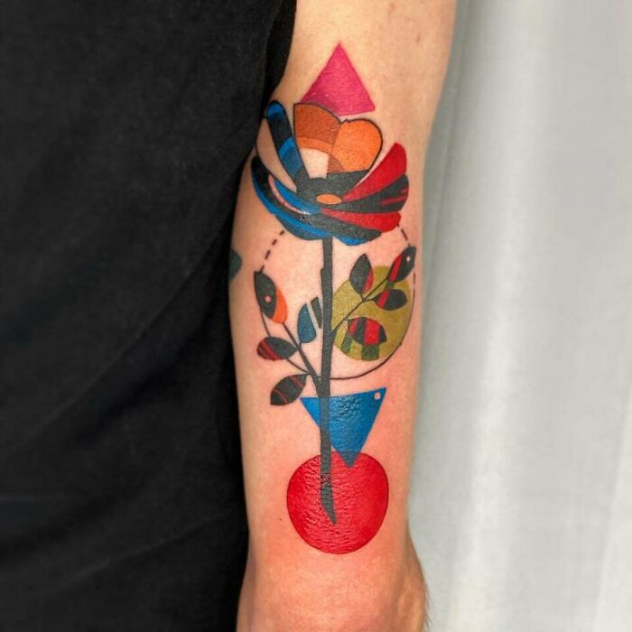 Colorful abstract tattoo of a geometric floral design on an arm, showcasing artistry and self-expression.