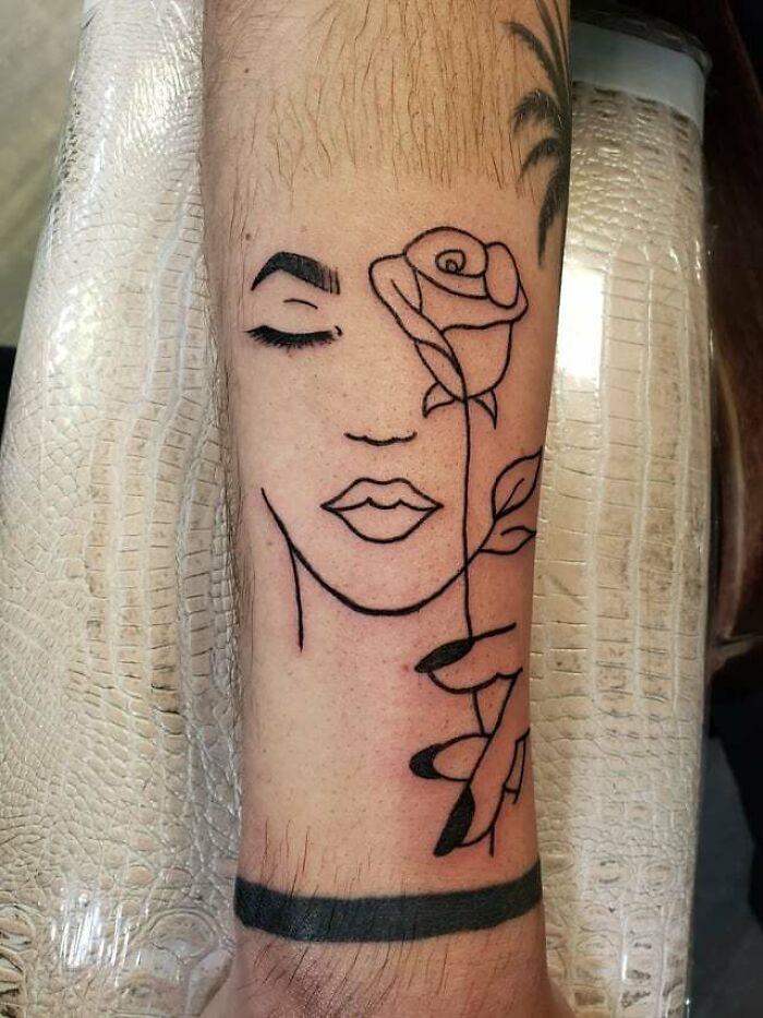 Abstract tattoo design of a face and rose on a forearm, showcasing artistry and self-expression.