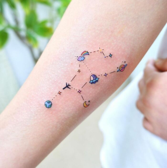 Colorful science tattoo featuring planets and stars on a forearm.