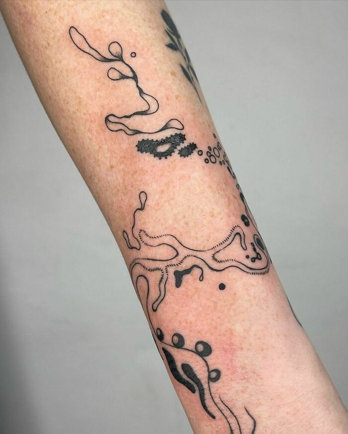Abstract tattoo design on forearm showcasing unique artistry and self-expression in black ink.