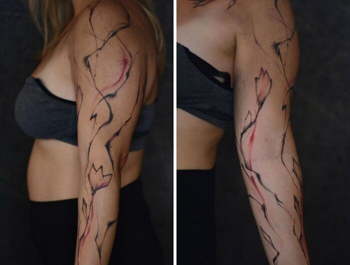 Abstract tattoo design on a woman's arm, showcasing artistry and self-expression with flowing black and red lines.