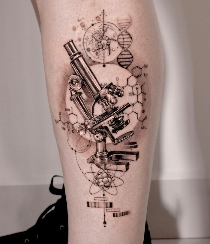 Microscope tattoo with DNA and molecular diagrams on leg, highlighting science-themed body art.
