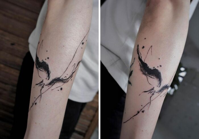Abstract tattoo on forearm with black ink, showcasing artistry and self-expression through fluid, artistic lines.
