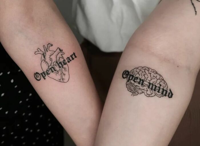 Two powerful mental health tattoos on forearms: one heart with "Open Heart" and one brain with "Open Mind" designs.