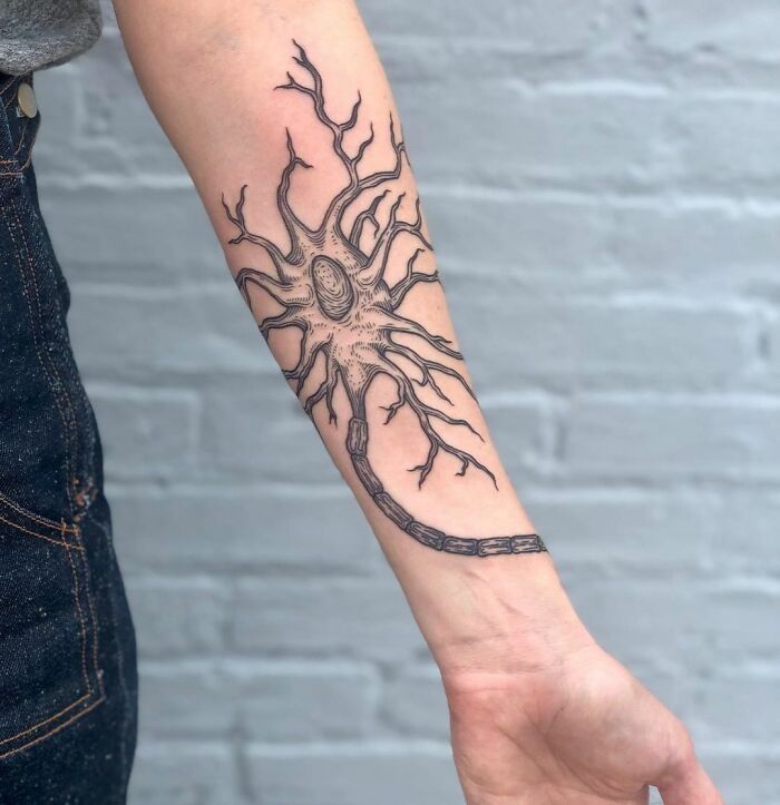 Tattoo of a neuron on a forearm, showcasing a detailed science-inspired design.