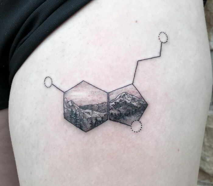 Mental health tattoo of a serotonin molecule with mountain landscape design on skin.