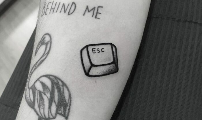 Mental health tattoos featuring an "ESC" key and a flamingo design on an arm.