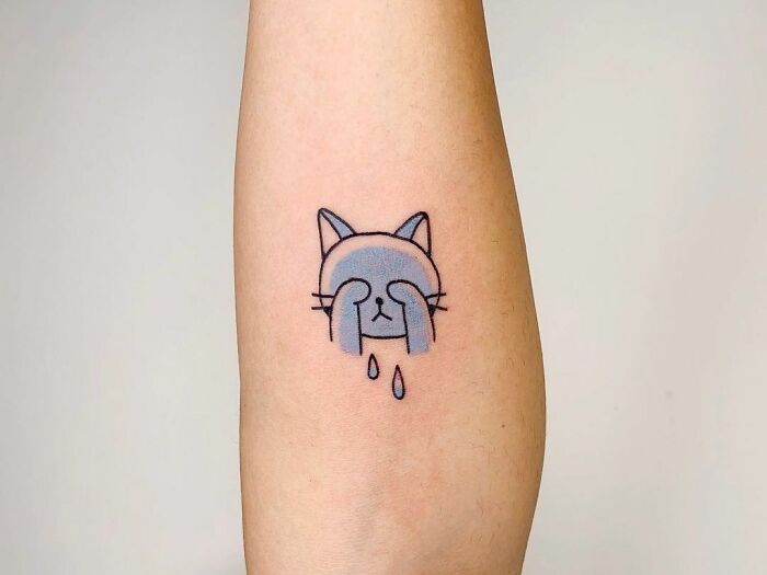Crying cat tattoo on forearm, symbolizing mental health healing.