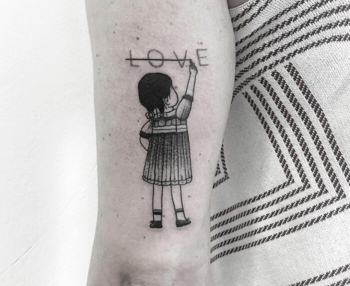 Tattoo of a child on an arm drawing the word "LOVE" with mental health themes.