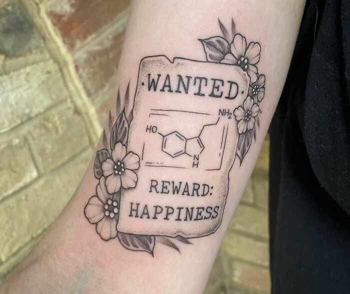 Mental health tattoo featuring a chemistry structure, text "Wanted: Reward: Happiness," surrounded by floral design.