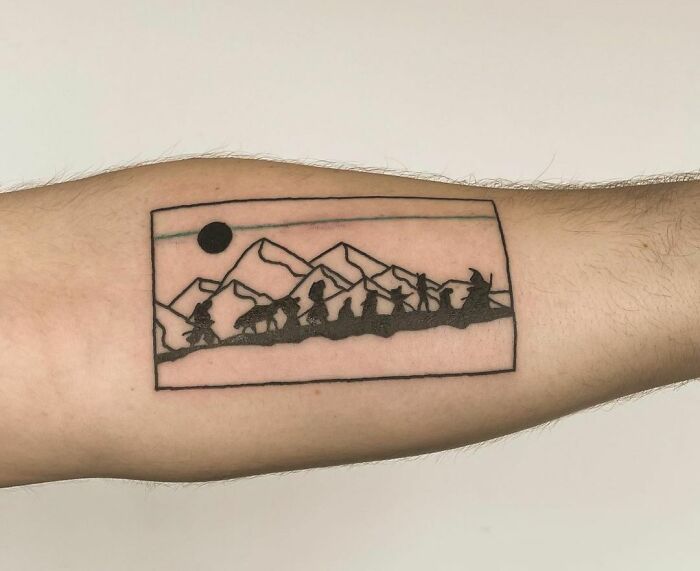 Minimalist Lord of the Rings tattoo depicting a mountain trek scene on a forearm.