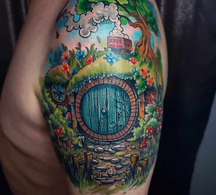 Colorful Hobbit door tattoo from Lord of the Rings with flowers and greenery surrounding it.