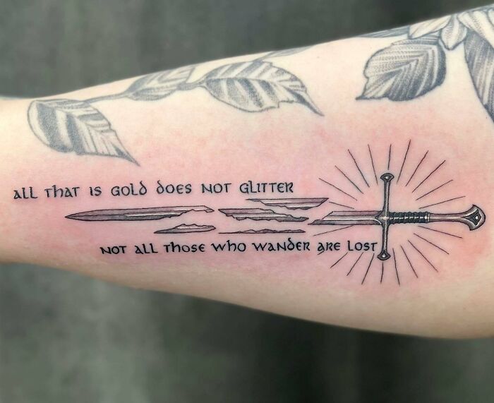 Tattoo of a sword with Elvish script and leaves, inspired by Lord of the Rings, featuring a famous quote from the series.