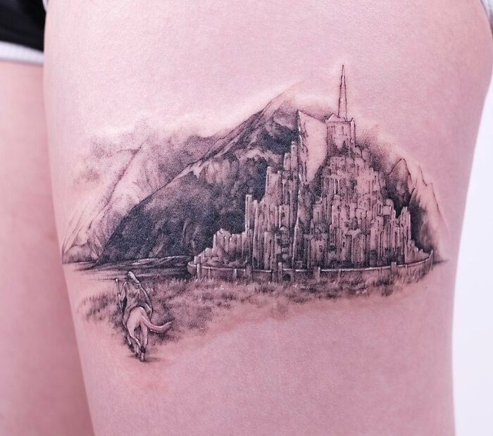 "Detailed Lord of the Rings tattoo featuring a mountain and fortress on a person's leg."