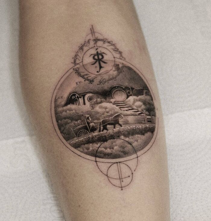 Lord of the Rings tattoo featuring a detailed landscape with a circular script design on an arm.