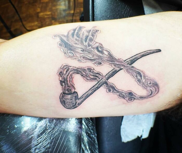 Lord of the Rings tattoo featuring a smoke-filled pipe with intricate design on a forearm.