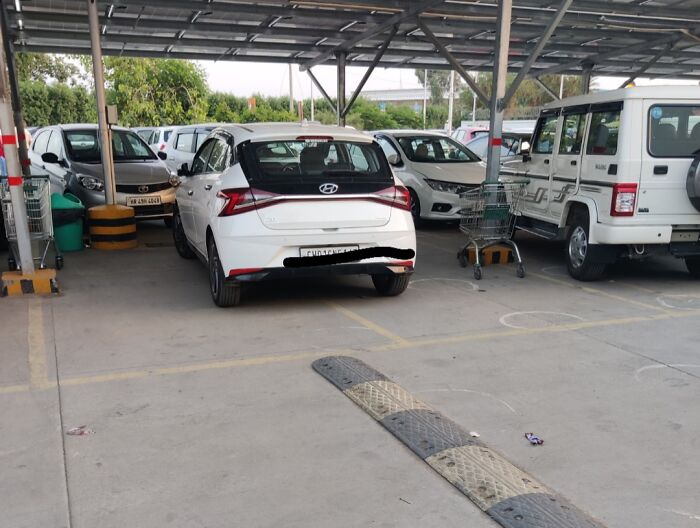 White car parked across two parking spaces in a covered lot, demonstrating entitled individuals' inconsiderate parking behavior.