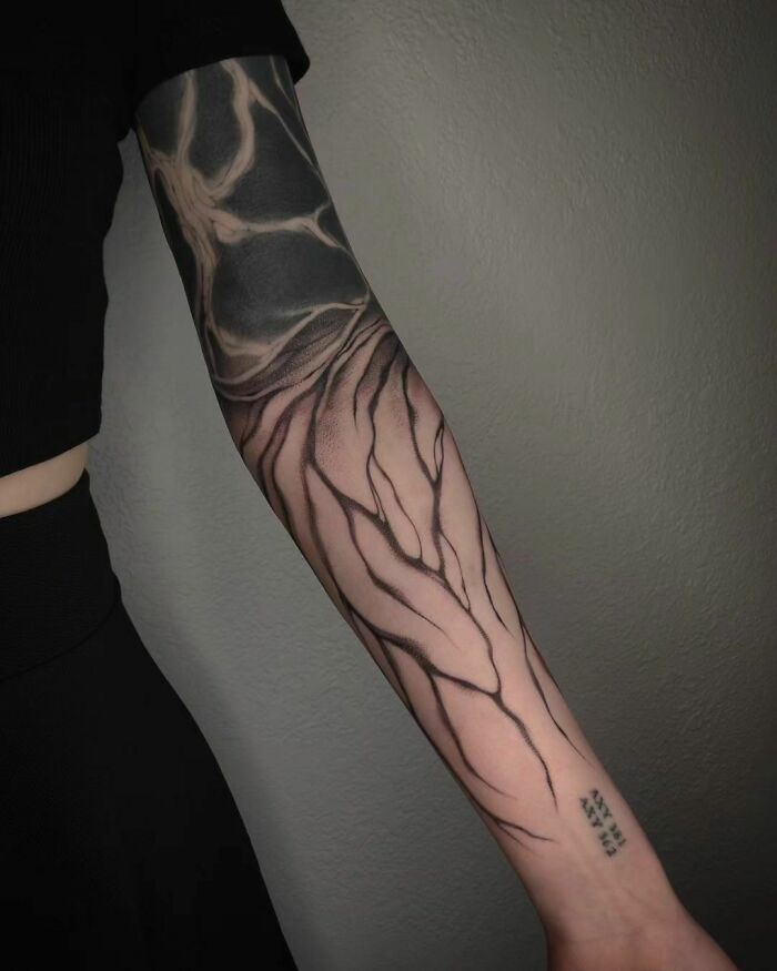 Abstract tattoo design on an arm with bold, swirling black lines and geometric patterns.