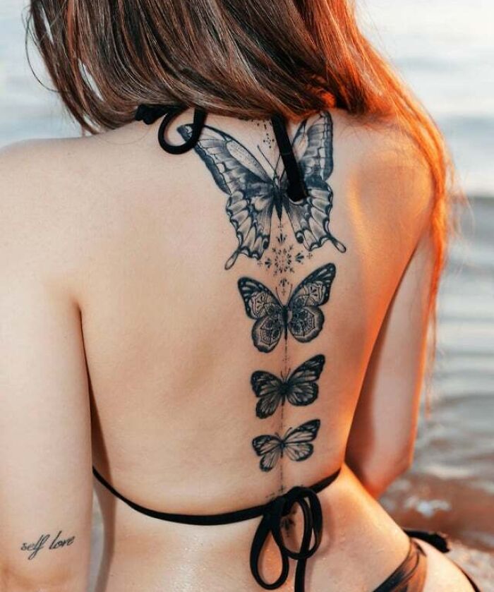 Butterfly tattoos on a woman's back in a vertical line, showcasing intricate designs and artistry.