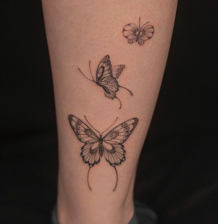 Three butterfly tattoos on a leg, intricately designed with detailed patterns.