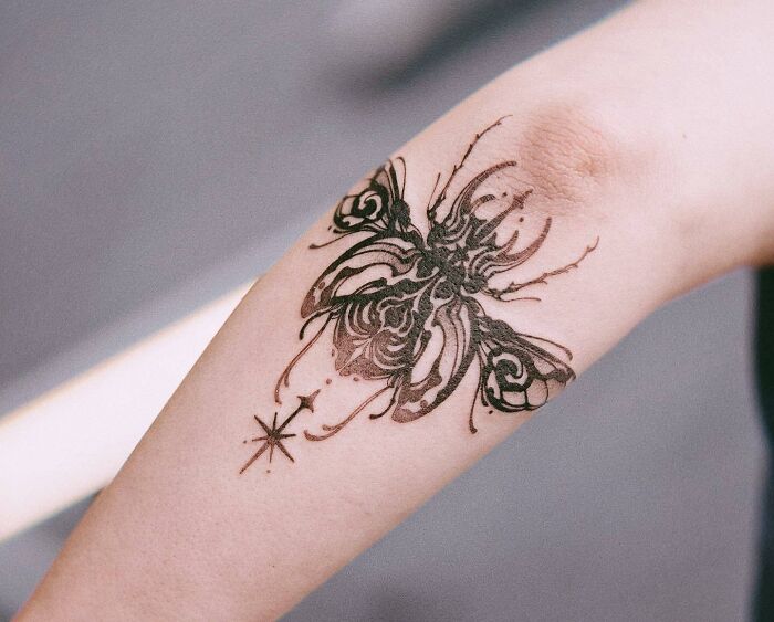 Detailed butterfly tattoo on forearm, inspired by the real thing, showcasing intricate patterns and lines.