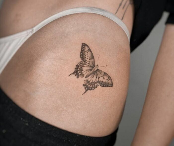 Black and gray butterfly tattoo on skin, showing realistic design and intricate details.
