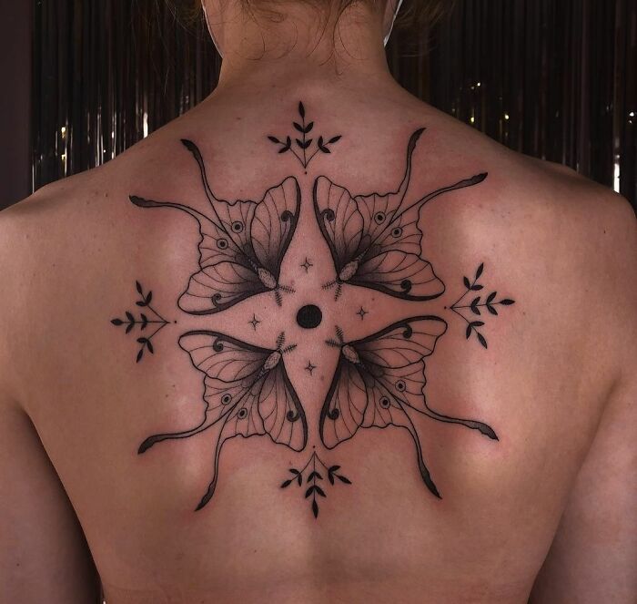 Geometric butterfly tattoos on a person's back, featuring intricate patterns and black ink design.