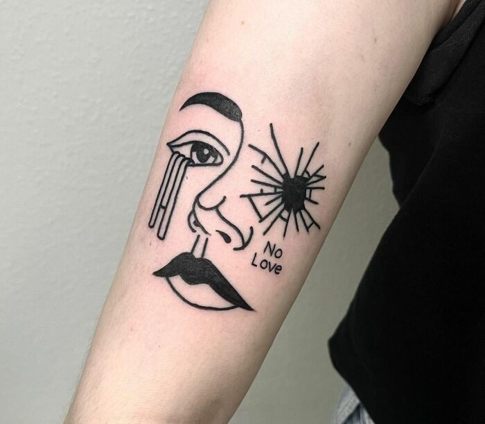 Arm with a powerful mental health tattoo of a face, one eye crying, and a shattered sun, with the text "No Love."