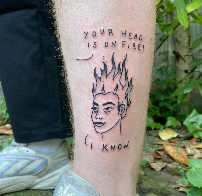 Tattoo on leg depicting a face with flaming hair and text discussing mental health.