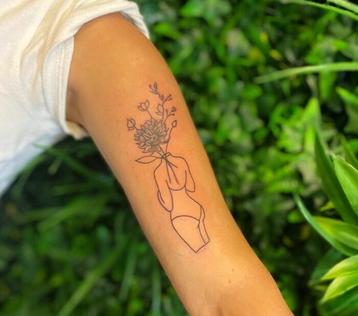 Line art tattoo on arm of a figure with a bouquet of flowers for mental health.