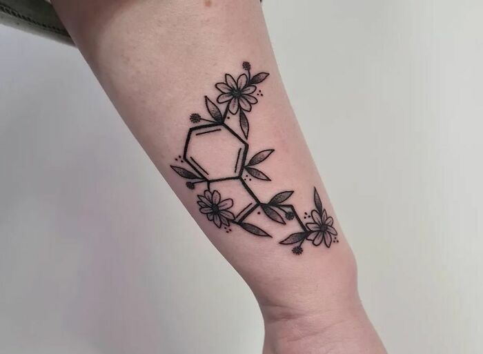 Floral and geometric mental health tattoo design on forearm, featuring chemical structure with flowers.