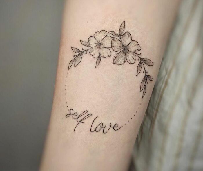 Tattoo of flowers with "self love" text, symbolizing healing and mental health awareness.