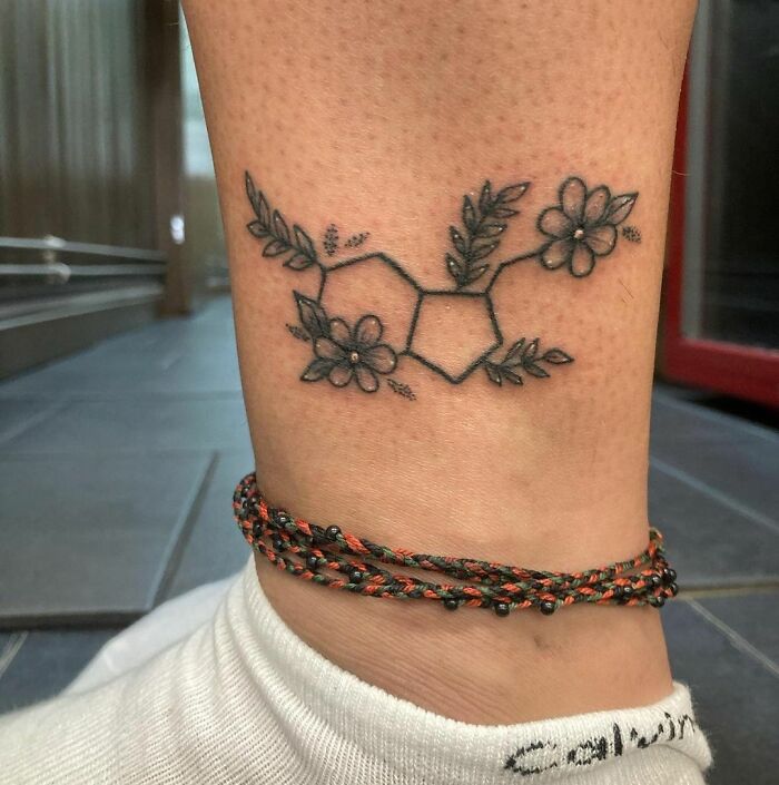 Floral serotonin molecule tattoo on ankle symbolizes mental health healing.