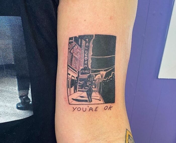 Mental health tattoo depicting a street scene with "YOU'RE OK" text for healing inspiration.