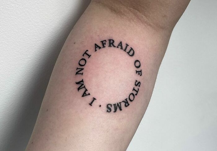 Tattoo with the phrase "I am not afraid of storms" in a circle, symbolizing mental health and healing.
