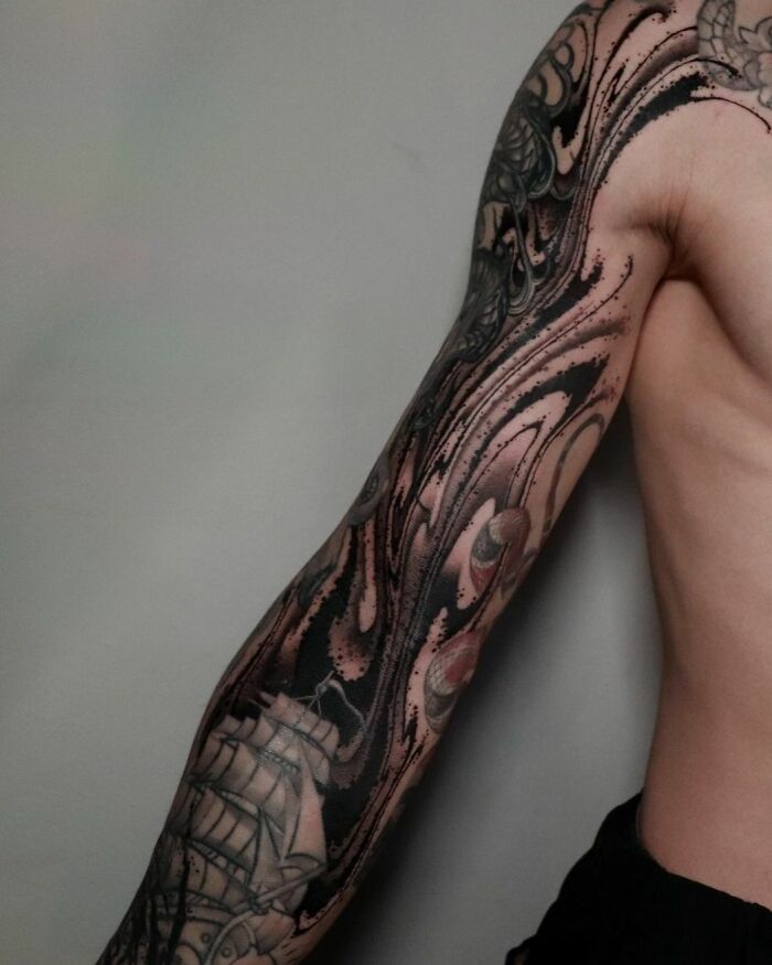 Abstract tattoo sleeve on an arm, showcasing intricate artistry and self-expression in swirling patterns.