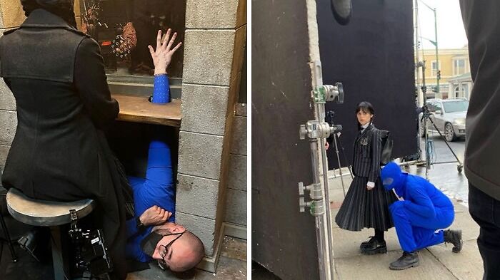 Behind-the-scenes of Wednesday Addams filming, with a crew member in blue adjusting props.