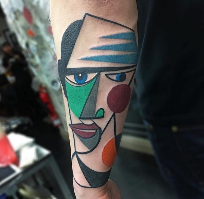 Abstract tattoo design on forearm with colorful geometric shapes and bold lines for self-expression.