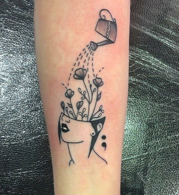 Mental health tattoo with flowers growing from head and a watering can, symbolizing growth and healing.