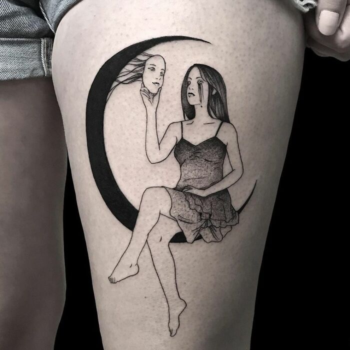 Tattoo of a woman sitting on a crescent moon, holding a mask, symbolizing mental health and healing.