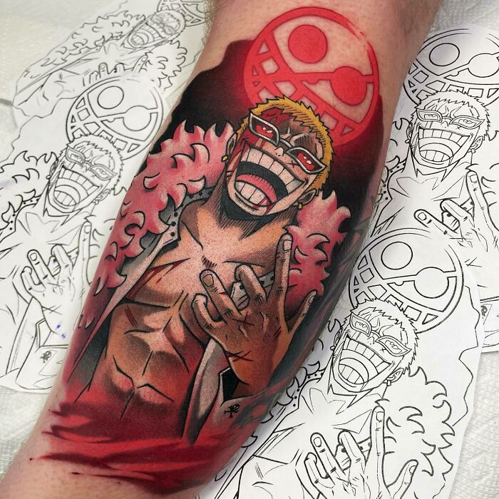 Colorful anime tattoo design featuring a grinning character with red glasses, surrounded by sketches.