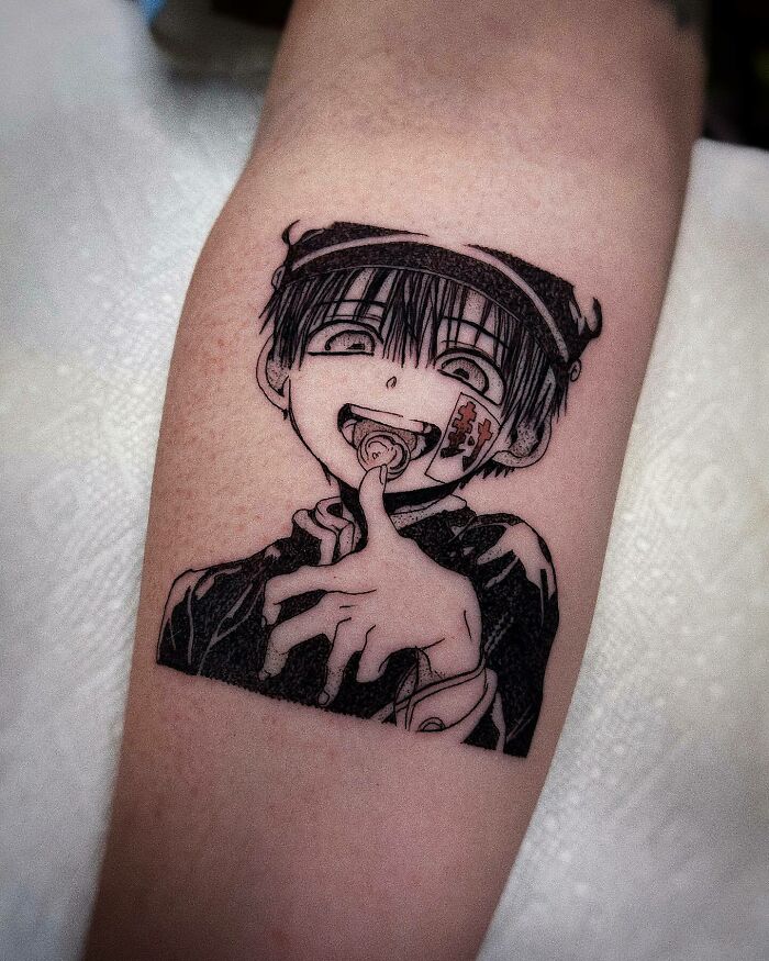 Anime tattoo depicting a smiling character with a hat and finger gesture, showcasing intricate line work.