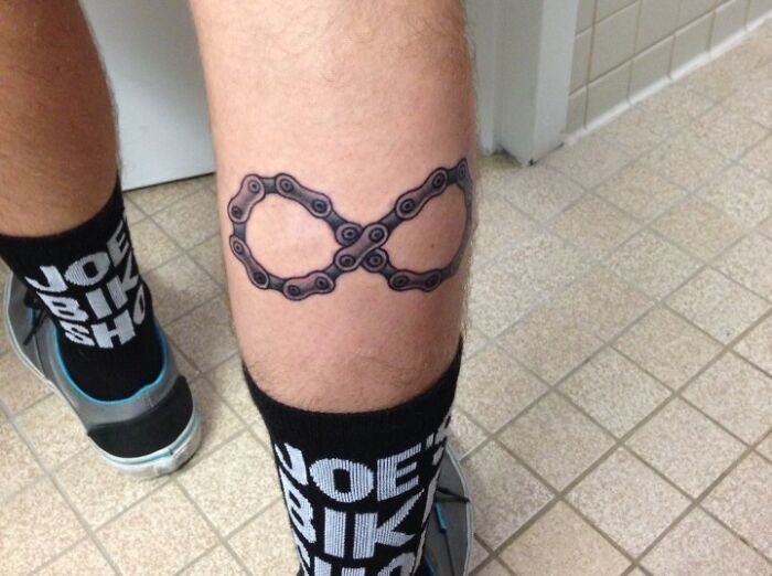 Infinity tattoo made of a bike chain on a person's leg, showcasing eternal creativity.