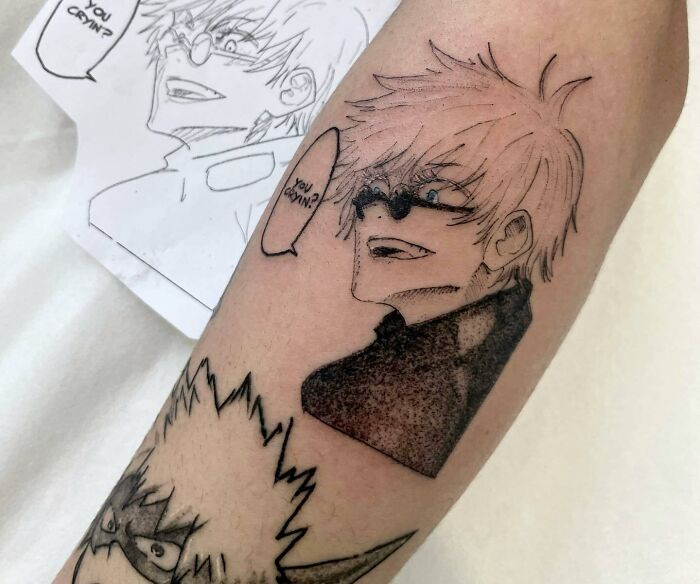 Anime tattoos on an arm, featuring characters with expressive faces and dialogue bubbles.