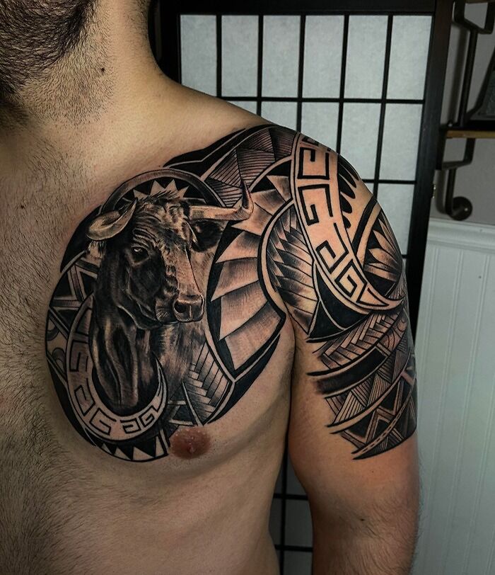 Detailed tribal tattoo with a bull design on a man's shoulder and chest.