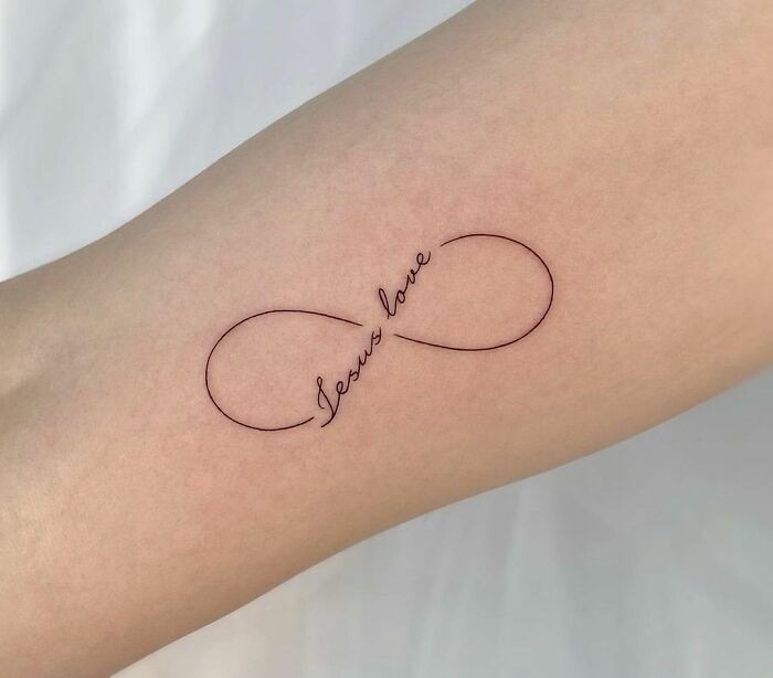 Infinity tattoo reading "Jesus love" on forearm symbolizing eternal creativity.